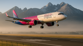 Lietadlo Wizz Air tesne pred pristátím nad prahom dráhy letiska Poprad-Tatry, v pozadí štíty Vysokých Tatier, nízky uhol od plota dráhy, ranné svetlo