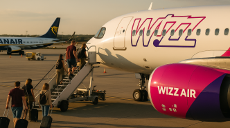 Nastup cestujucich po schodoch do lietadla Wizz Air Airbus A321neo na ploche letiska, v pozadi Boeing 737 Ryanair, letne neskore popoludnie