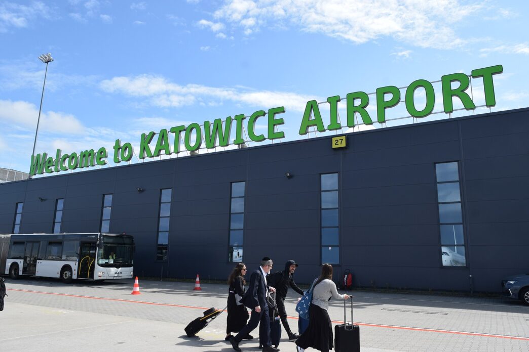 Cestujúci s batožinou pred terminálom letiska Katowice