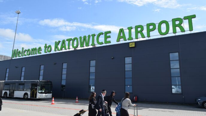 Cestujúci s batožinou pred terminálom letiska Katowice