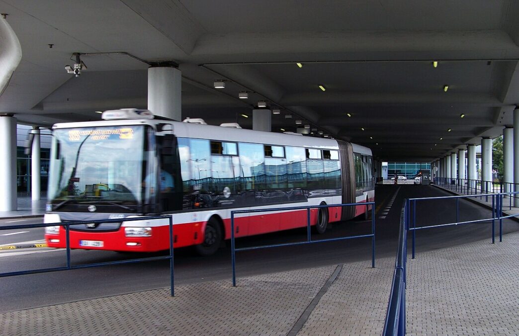 Mestský kĺbový autobus zastavuje pred letiskovým terminálom
