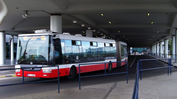 Mestský kĺbový autobus zastavuje pred letiskovým terminálom