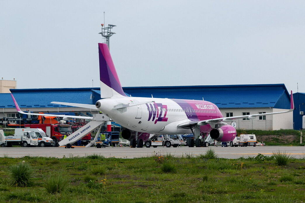Lietadlo Wizz Air pri termináli s pristavenými schodíkmi a cestujúcimi na ploche