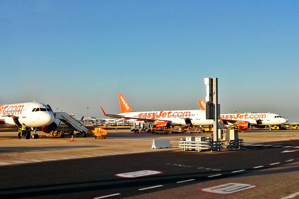 Tri lietadlá easyJet v oranžovo-bielom nátere stoja na letiskovej ploche, pri prvom je pristavené schodisko a pozemná technika.