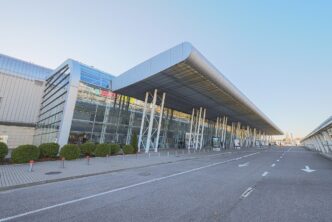 Presklená budova terminálu letiska Ľvov so zakriveným strešným prístreškom a príjazdovou cestou za slnečného dňa