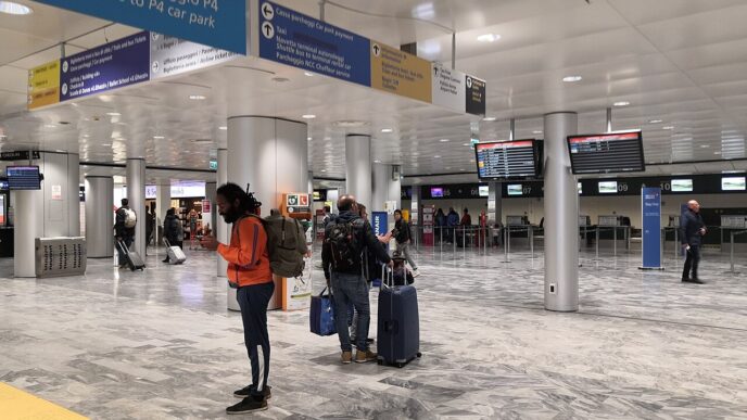 Svetlá odletová hala terminálu s cestujúcimi s kuframi, informačnými monitormi a smerovými tabuľami pod stropom